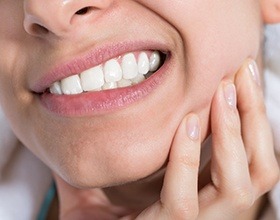 Woman grimacing and holding jaw before T M J therapy