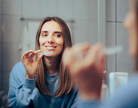 Woman smiling in the mirror and holding her nightguard