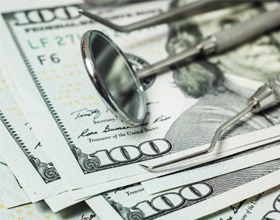 Dental tools stacked on top of dollar bills