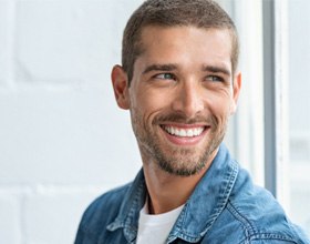 Man with dental crowns in Chesterfield smiling inside a building