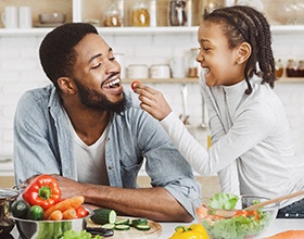 a man smiling and eating with his child