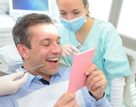 a patient checking his teeth with a mirror