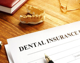 a dental insurance form next to wax teeth