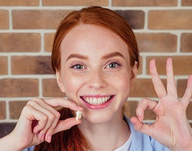 Woman smiling and holding tooth after tooth extraction in Chesterfield