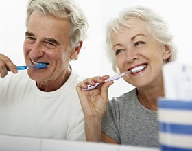 elderly couple brushing their teeth together 