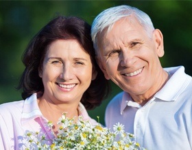 Smiling older man and woman with dental implant retained dentures outdoors