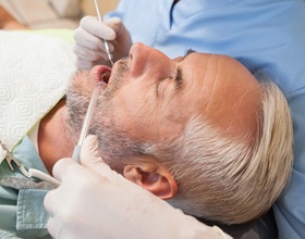 Older man laying in dental chair receiving a checkup