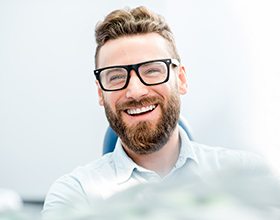 young, bearded man with glasses smiling 