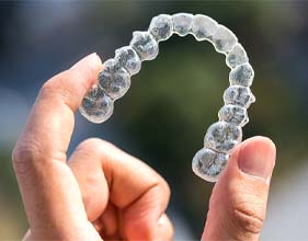 Hand holding up Invisalign aligner