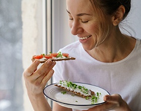 Woman smiling while eating healthy meal at home