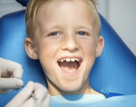 Happy little boy in the dental chair for first children's dentistry visit