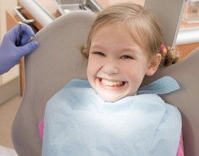 Smiling girl in the dental chair for first children's dental office visit