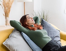 Woman lying back on pillows on couch 