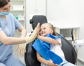Happy child high-fiving dental team member