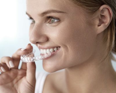 Woman placing Invisalign clear aligner tray over her teeth