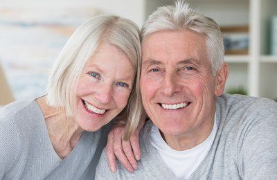 Grinning senior man and woman in gray sweaters