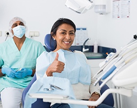 Woman giving a thumbs-up at her dental appointment 
