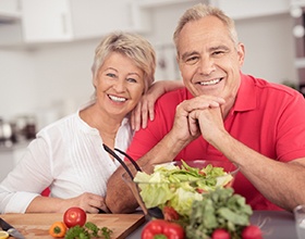 Older couple smiling while preparing a salad