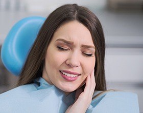 Woman holding jaw in pain before emergency dentistry visit