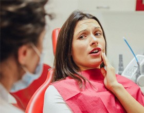 a patient touching her cheek due to tooth pain