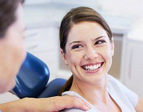 Smiling woman at dental office for dental crown and bridge restoration