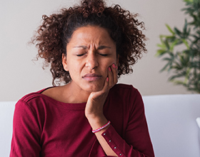 Woman with toothache sitting on couch at home