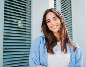 Woman with white teeth smiling while standing outside