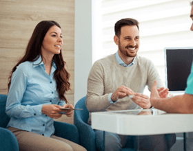 Smiling couple talking to dentist in their office