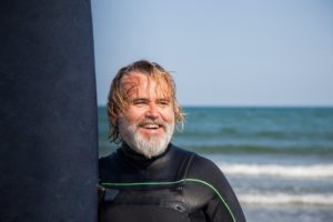 surfer smiling by the ocean 