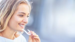 attractive woman holding Invisalign aligner