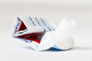 Empty, rolled-up tube of toothpaste on white background