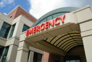 Entry archway to an emergency room with red letters spelling emergency