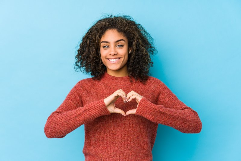 person smiling and making a heart with their fingers