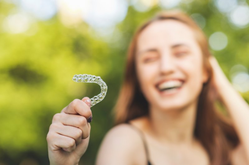 Young woman holding her invisalign aligner 